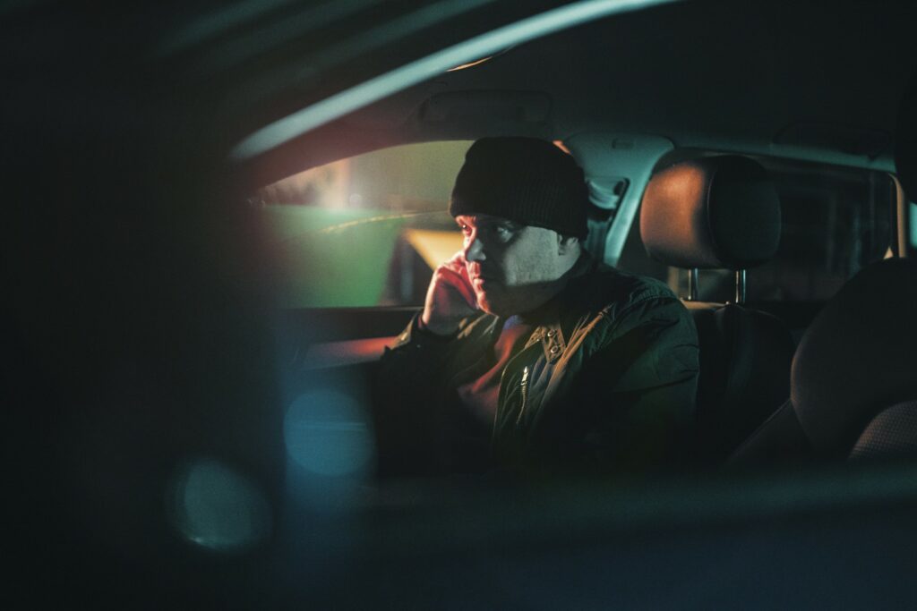 A man sitting in a car at night on his own
