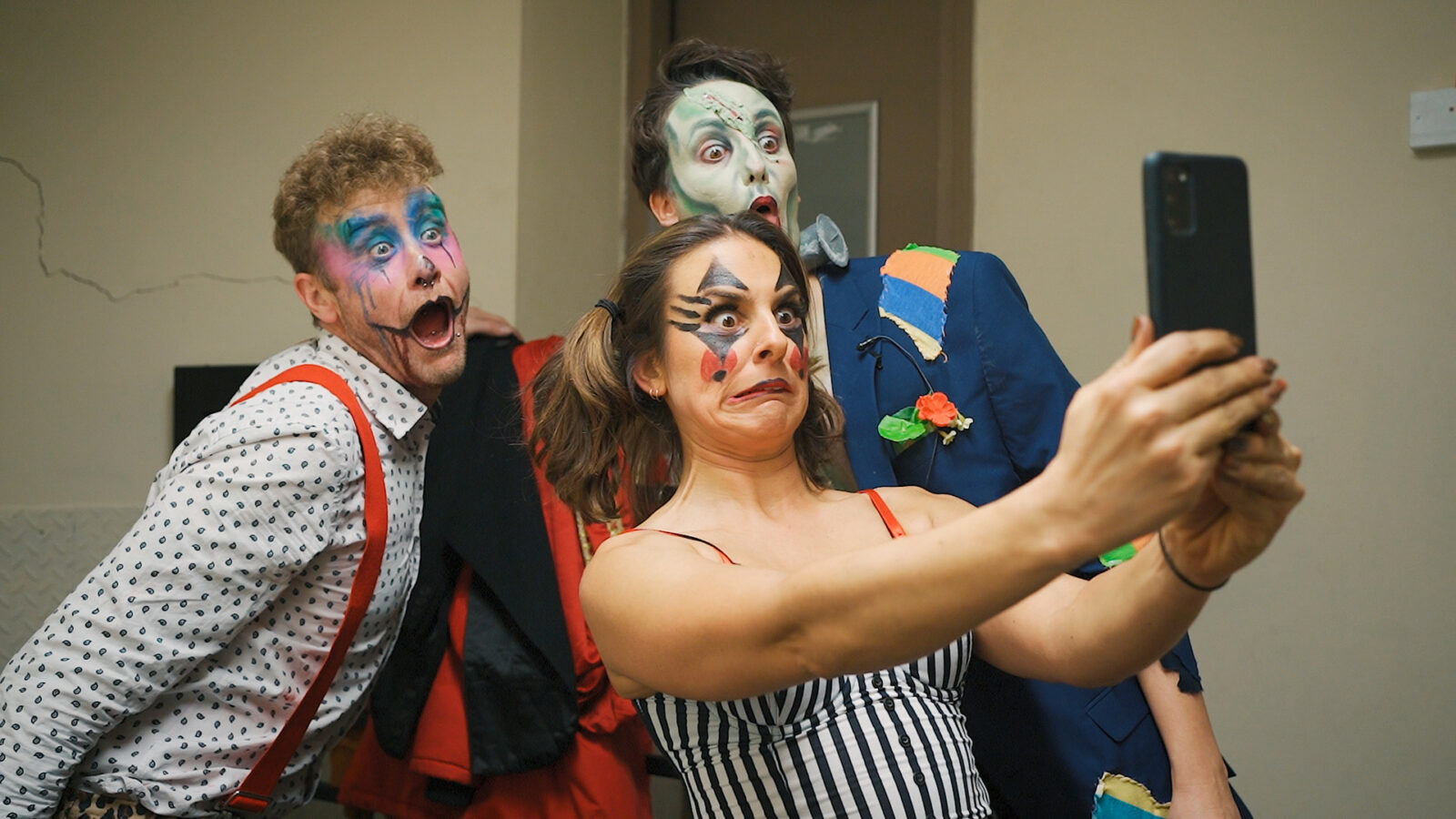 Three performers in stage make up taking a selfie